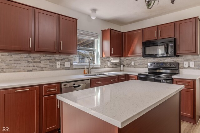 kitchen featuring light stone countertops, a sink, a center island, decorative backsplash, and black appliances