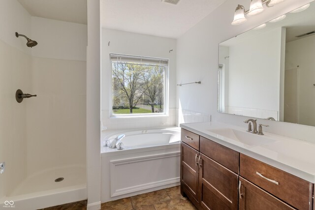 bathroom with visible vents, walk in shower, a bath, and vanity