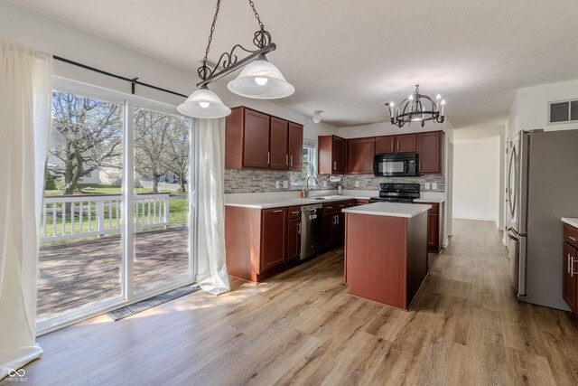 kitchen featuring a chandelier, light wood-type flooring, tasteful backsplash, visible vents, and black appliances