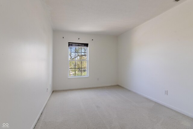 empty room featuring baseboards and light carpet