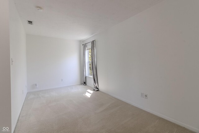 spare room with visible vents, baseboards, and light colored carpet