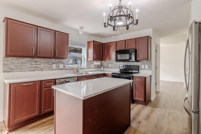 kitchen featuring a sink, a chandelier, light wood-style flooring, backsplash, and black appliances