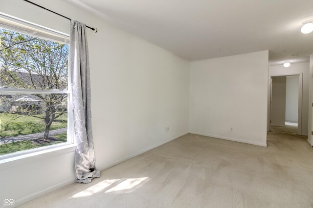 unfurnished room featuring baseboards, a wealth of natural light, and light carpet