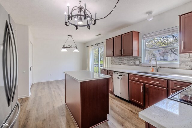 kitchen with decorative backsplash, a center island, a sink, light wood-style flooring, and stainless steel appliances
