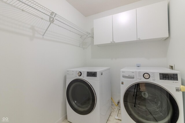 clothes washing area with baseboards, cabinet space, and washer and dryer