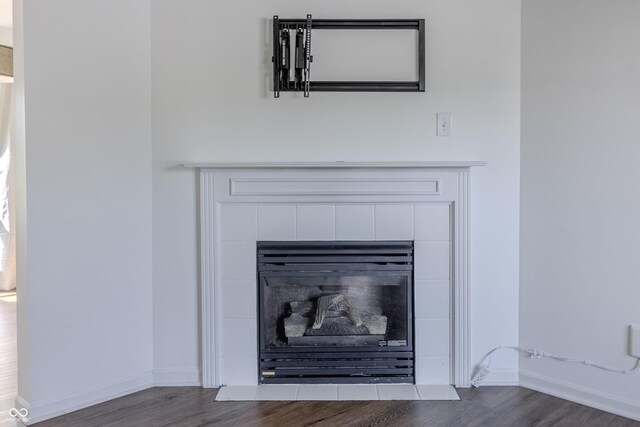 interior details featuring a tiled fireplace, baseboards, and wood finished floors