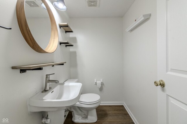 bathroom with toilet, baseboards, visible vents, and wood finished floors