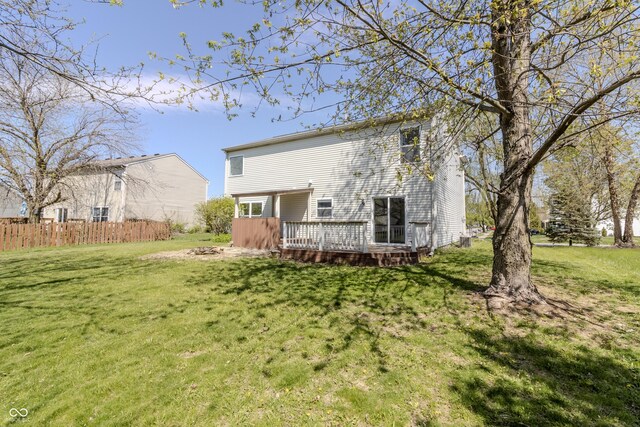 back of house featuring a lawn, a deck, and fence