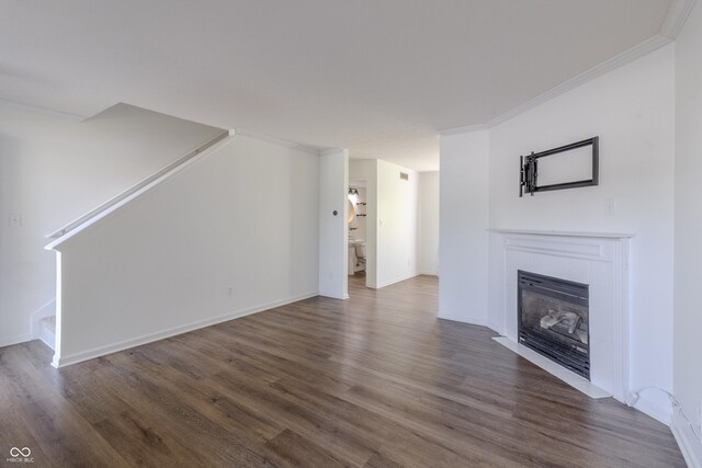 unfurnished living room with baseboards, ornamental molding, wood finished floors, and a fireplace