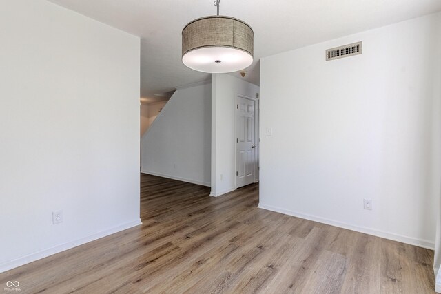 spare room with visible vents, baseboards, and wood finished floors