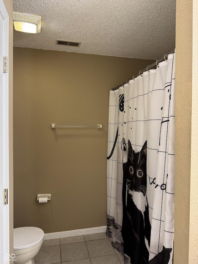 bathroom with tile patterned flooring, visible vents, toilet, baseboards, and a textured ceiling