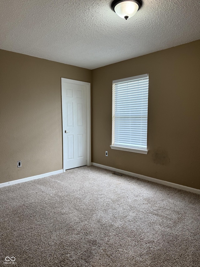 carpeted empty room featuring baseboards and a textured ceiling