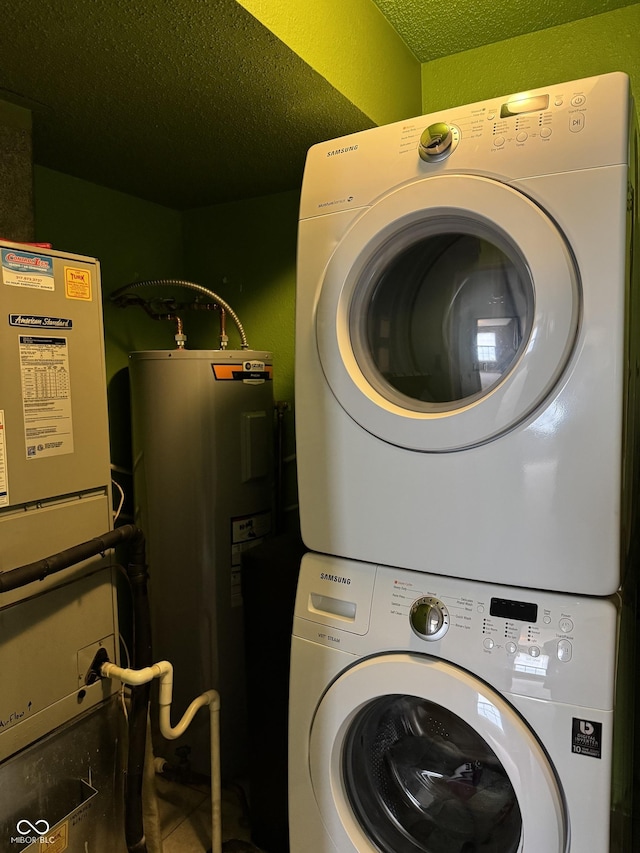 laundry room with stacked washer / drying machine, electric water heater, a textured ceiling, and laundry area