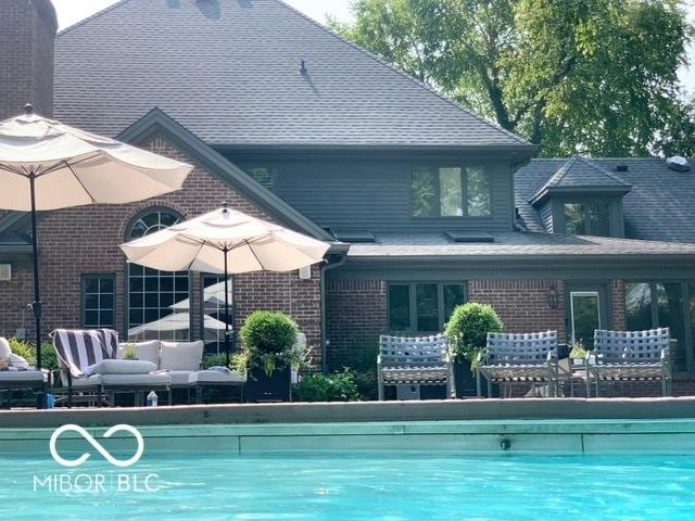 rear view of house featuring an outdoor hangout area, a community pool, and brick siding