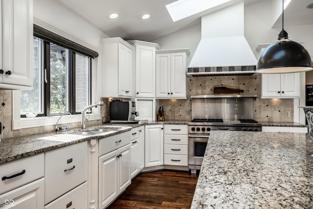 kitchen featuring a sink, custom exhaust hood, backsplash, and high end stainless steel range