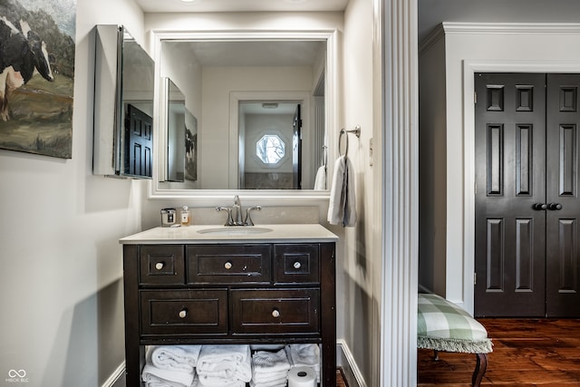 bathroom with wood finished floors, vanity, and baseboards