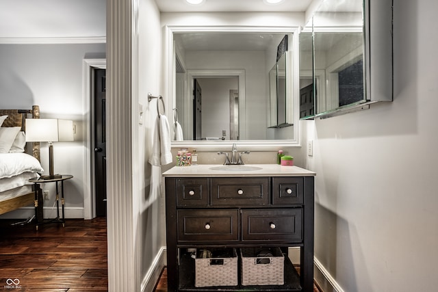 bathroom featuring wood finished floors, vanity, ornamental molding, and baseboards