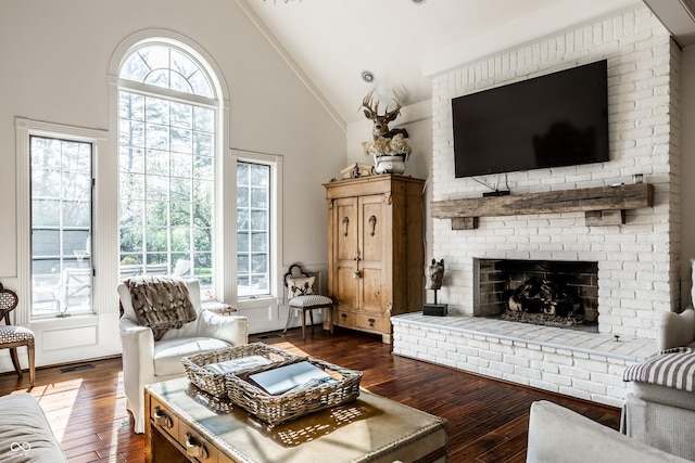 living area featuring dark wood finished floors, high vaulted ceiling, visible vents, and a brick fireplace