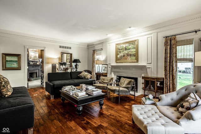 living area with a fireplace, visible vents, hardwood / wood-style flooring, and ornamental molding