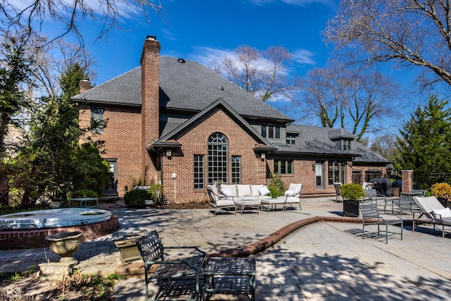 rear view of house with a patio, an outdoor hangout area, roof with shingles, a covered hot tub, and brick siding