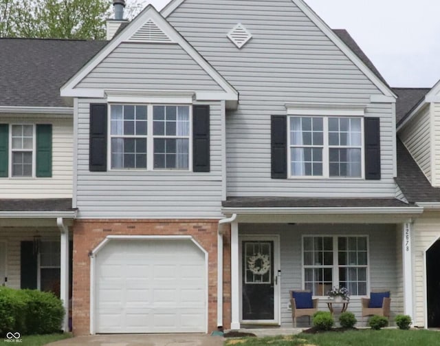 view of front of home with a porch, an attached garage, a chimney, and brick siding