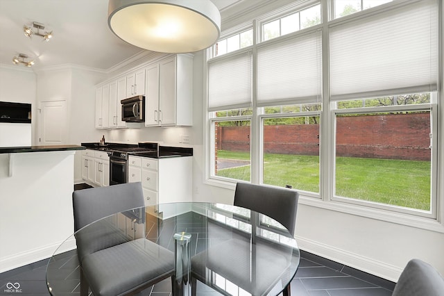 dining space with dark tile patterned floors, ornamental molding, and baseboards