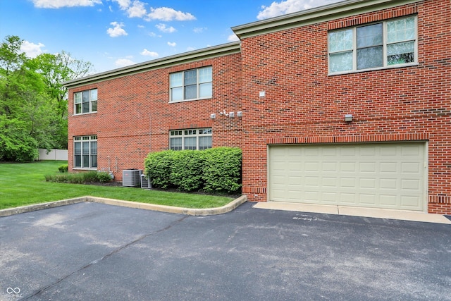 view of front of property with brick siding, an attached garage, asphalt driveway, and a front lawn