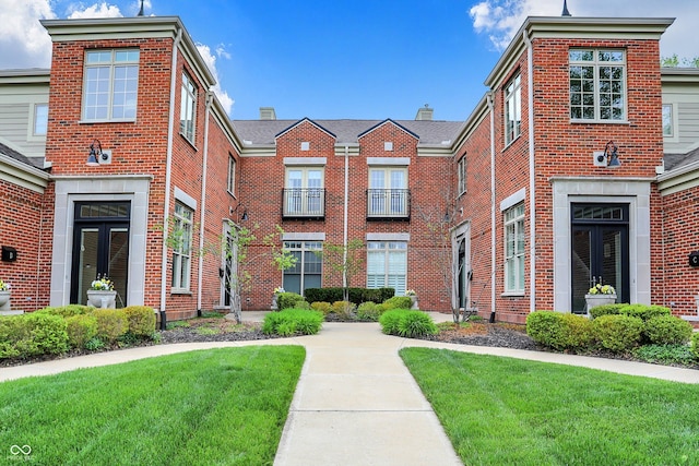 townhome / multi-family property featuring brick siding and a front lawn