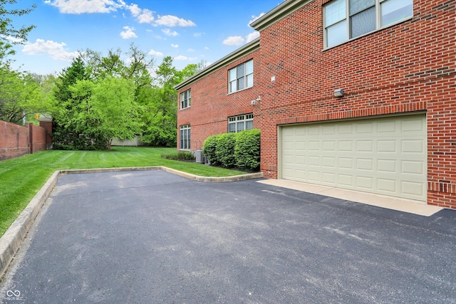 view of side of property featuring brick siding, an attached garage, central AC unit, and driveway