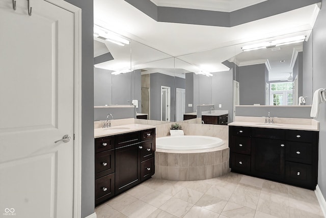 bathroom with ornamental molding, a bath, and two vanities