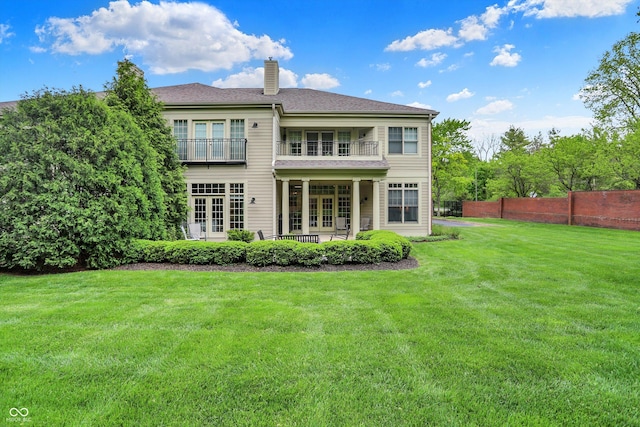 rear view of property with french doors, a balcony, a chimney, and a patio area