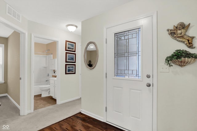 entrance foyer with baseboards, visible vents, and dark colored carpet