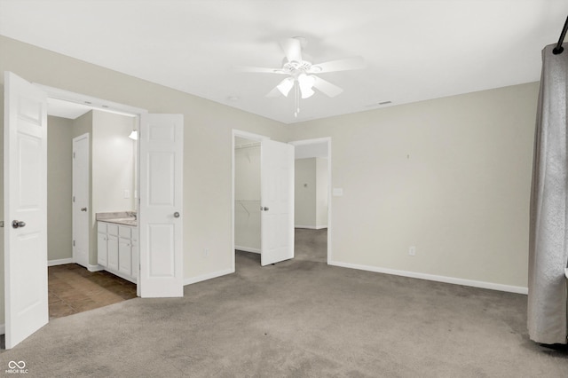 unfurnished bedroom with ceiling fan, carpet floors, baseboards, a spacious closet, and a closet
