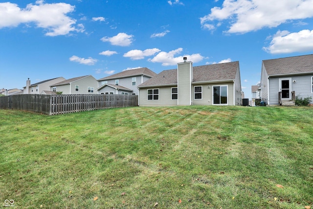 rear view of property featuring fence, a chimney, and a lawn