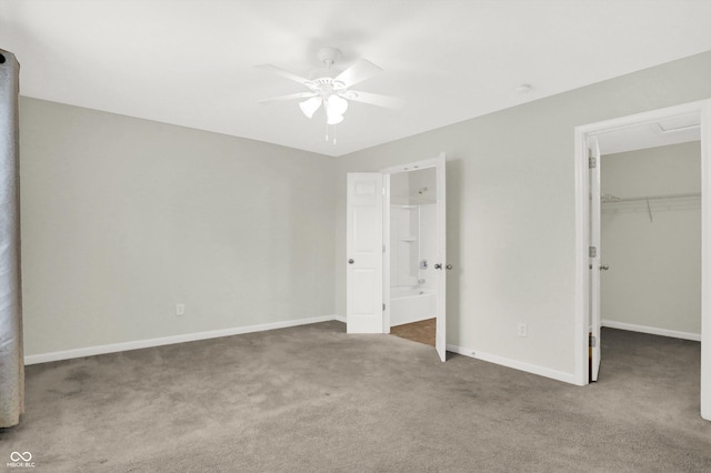 unfurnished bedroom with a closet, a walk in closet, baseboards, and carpet flooring