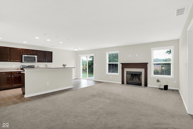 kitchen featuring visible vents, dark brown cabinetry, range with electric stovetop, stainless steel microwave, and a tiled fireplace