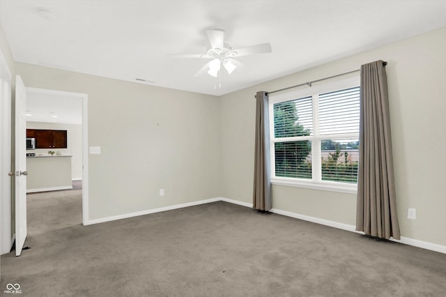 carpeted empty room featuring ceiling fan, visible vents, and baseboards