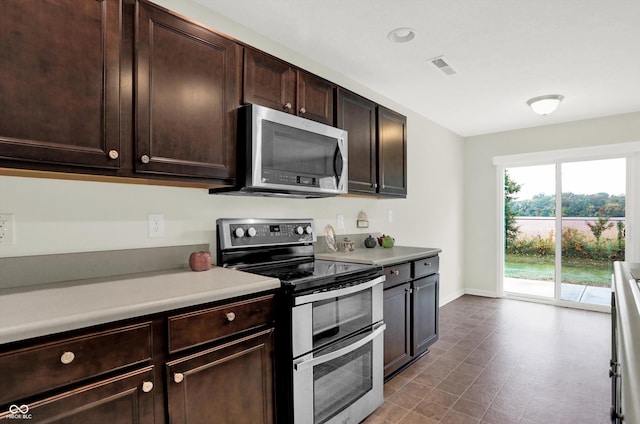 kitchen featuring baseboards, light countertops, appliances with stainless steel finishes, and dark brown cabinets