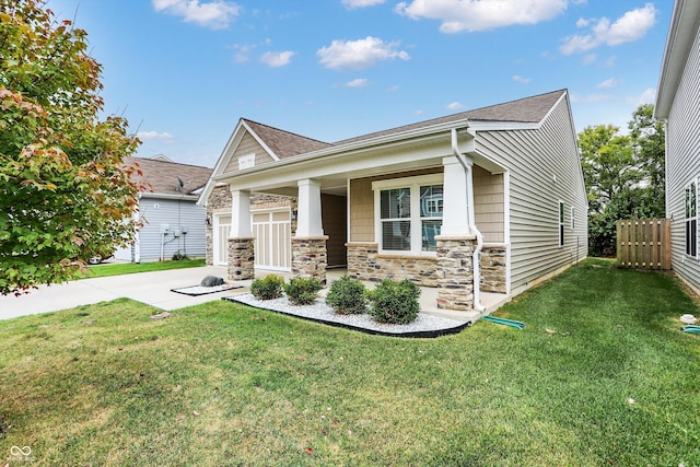 craftsman-style house with a front lawn, fence, covered porch, and stone siding