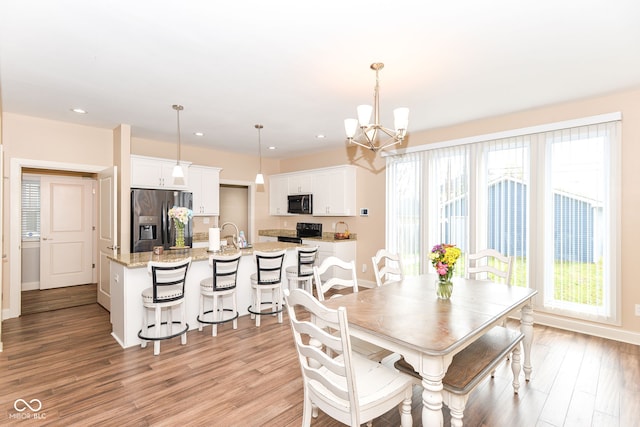 dining space with recessed lighting, light wood-style flooring, a healthy amount of sunlight, and a notable chandelier