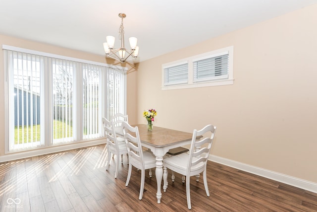 dining room with an inviting chandelier, a healthy amount of sunlight, dark wood-type flooring, and baseboards