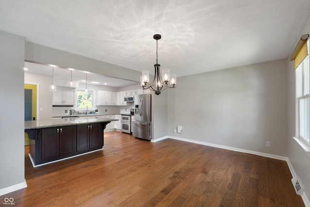 kitchen with visible vents, appliances with stainless steel finishes, a sink, white cabinets, and a chandelier