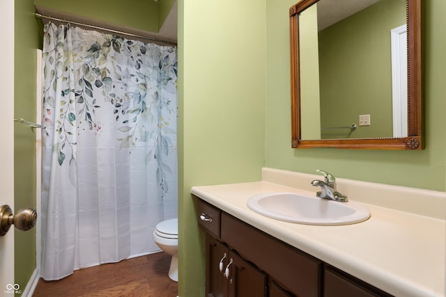 bathroom featuring toilet, curtained shower, wood finished floors, and vanity