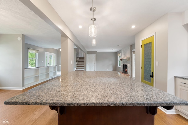 kitchen with a fireplace, a breakfast bar area, light wood-style flooring, open floor plan, and a large island