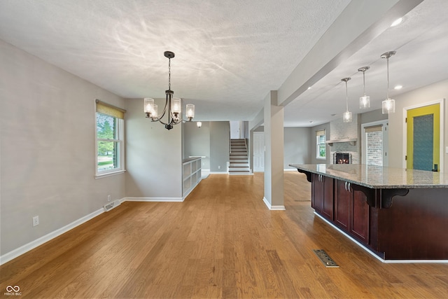 kitchen with light wood finished floors, open floor plan, baseboards, a kitchen bar, and visible vents