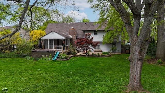 back of property with fence, a lawn, a chimney, and a sunroom