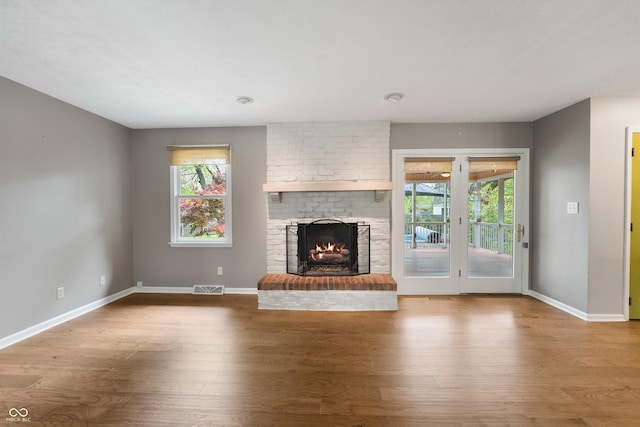 unfurnished living room featuring visible vents, a healthy amount of sunlight, wood finished floors, and a fireplace