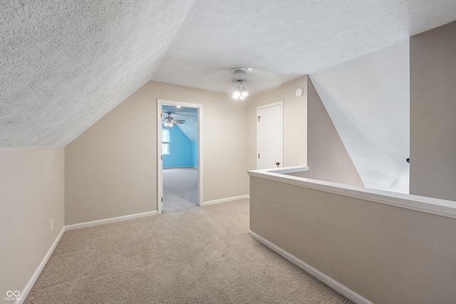 additional living space featuring a textured ceiling, carpet, baseboards, and lofted ceiling