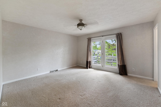 unfurnished room with visible vents, carpet flooring, baseboards, and a textured ceiling