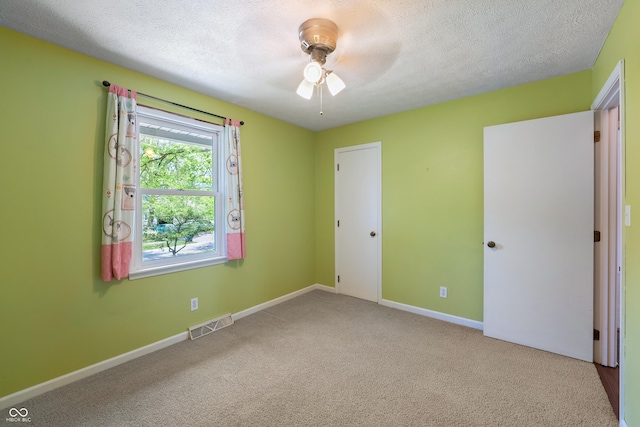 unfurnished bedroom with a textured ceiling, visible vents, baseboards, and carpet